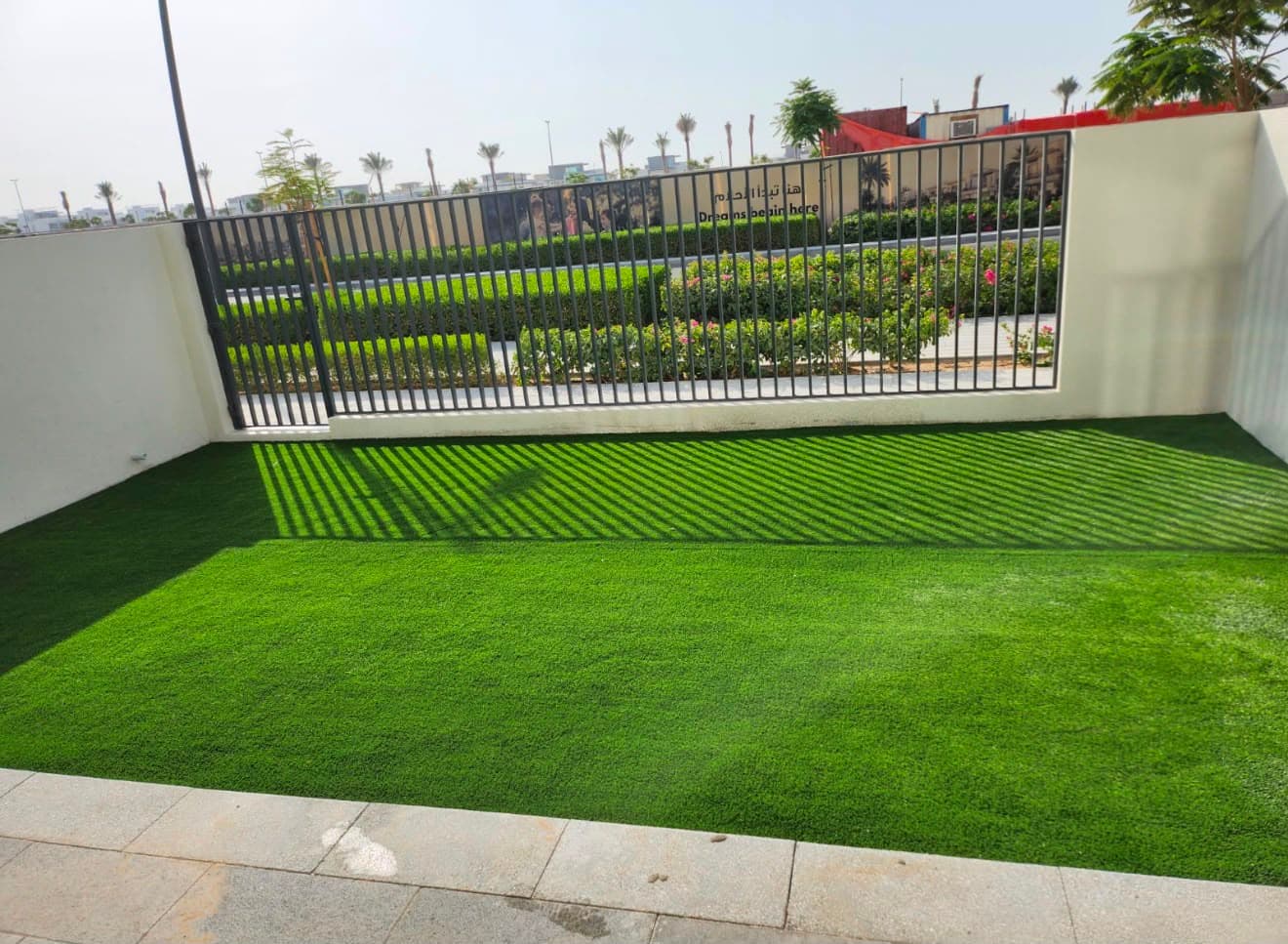 Artificial grass lawn laid to a villa garden, edged with porcelain paving and boundary railings