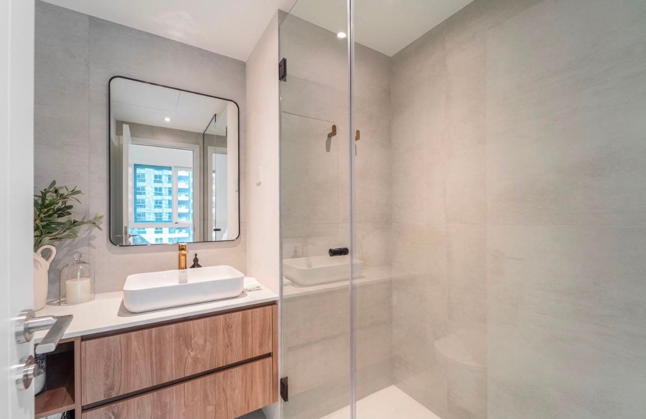 Refurbished bathroom with large-format grey tiling, a glass shower screen and a timber wall-hung vanity