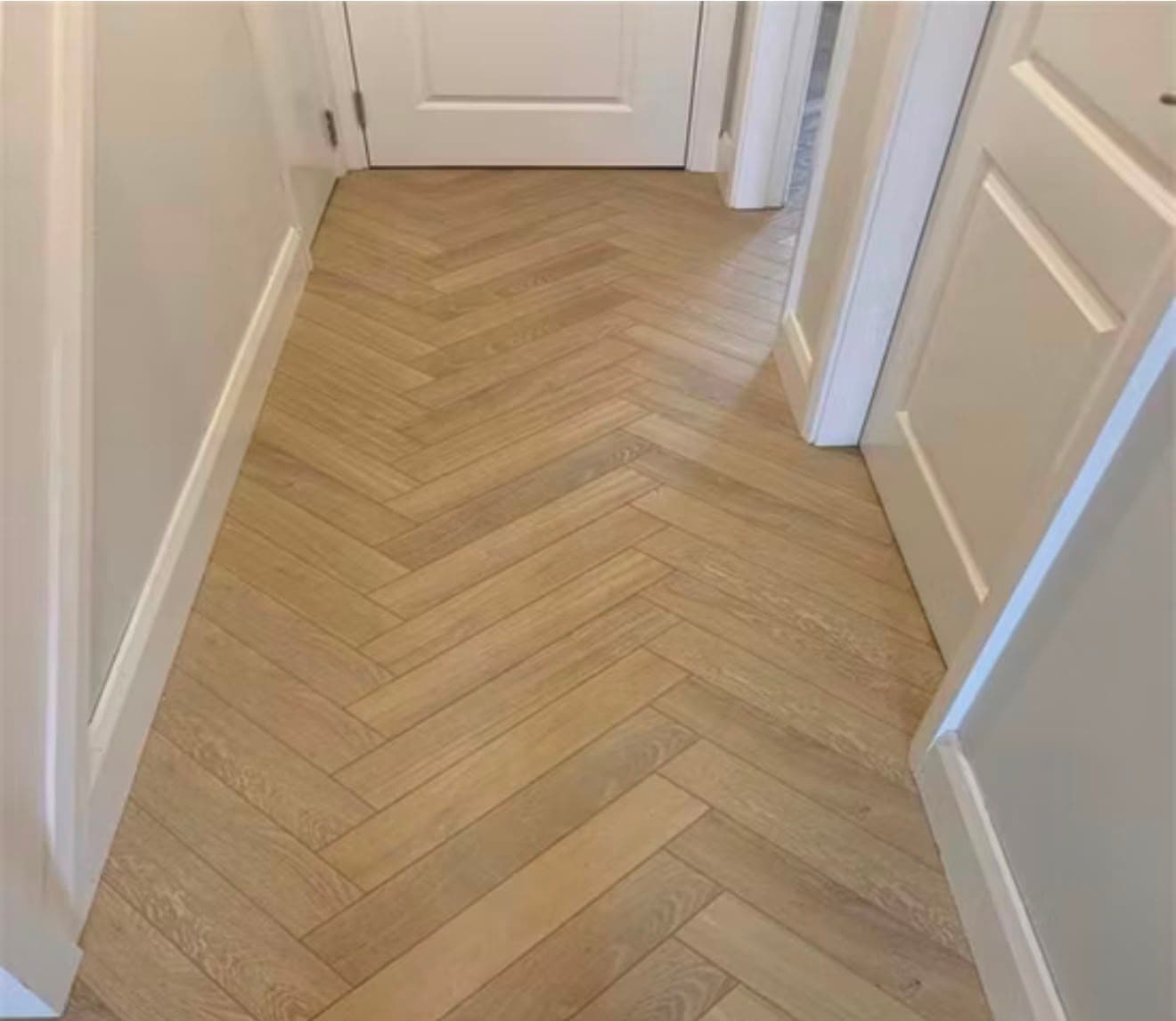 Herringbone LVT flooring laid through a hallway with painted skirting and doors
