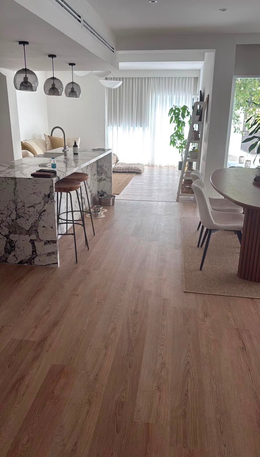 Open-plan living and dining space with wide-plank LVT flooring and a marble breakfast island