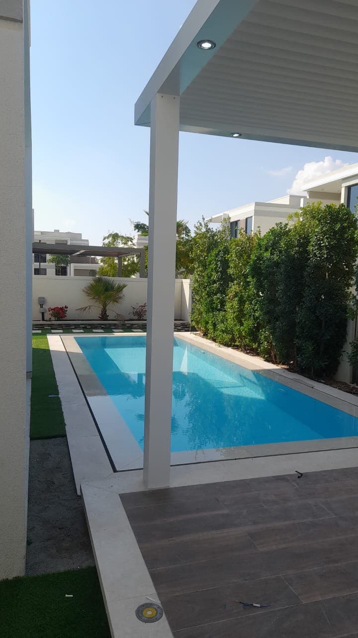 Pool terrace with a louvred shade structure, artificial grass and porcelain-tiled decking