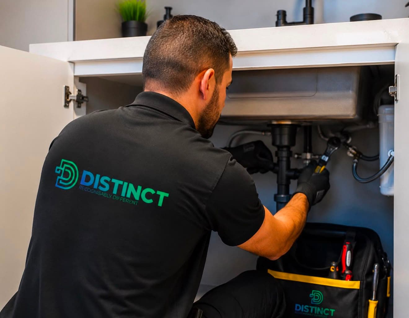 A Distinct Solutions technician in branded uniform carrying out plumbing work in a Dubai property